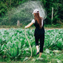 Mujer regando cultivos con una manguera - Imagen nota de cómo cuidar el agua